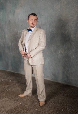 Klasik takım elbiseli yakışıklı adam duvarın yanında duruyor.