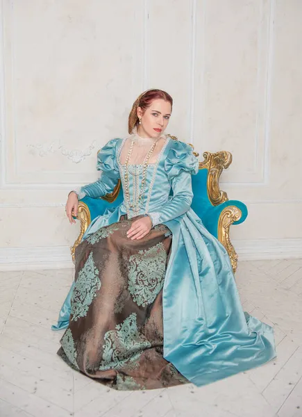 身着中世纪风格蓝色衣服的年轻貌美女子坐在扶手椅上 — 图库照片