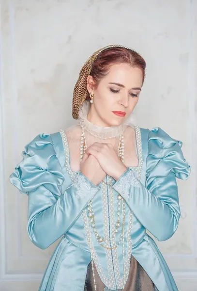 悲しいです美しい若い女性で中世のスタイルの青いドレススタンドで部屋 — ストック写真