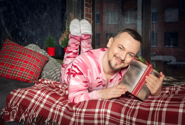 陽気な幸せな面白いです男でピンクベッドの上に置かクリスマスプレゼント — ストック写真