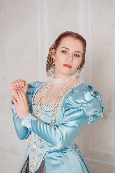 美しいです若い女性で中世のスタイルの青いドレススタンドで部屋 — ストック写真