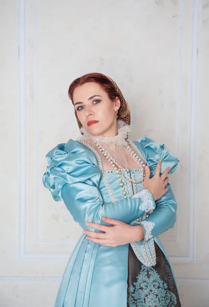 房间里站着穿着中世纪风格蓝色衣服的年轻貌美的女人 — 图库照片