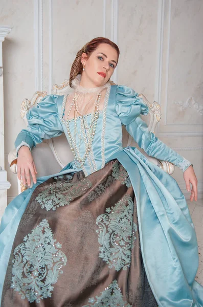 身着中世纪风格蓝色衣服的年轻貌美女子坐在扶手椅上 — 图库照片