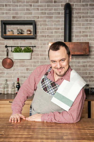 Vtipný Hezký Mladý Usměvavý Muž Nosí Pinafore Ručníkem Kuchyňce — Stock fotografie