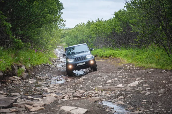 Suv car driving on a dirt off road with puddles and stones in the forest outdoo