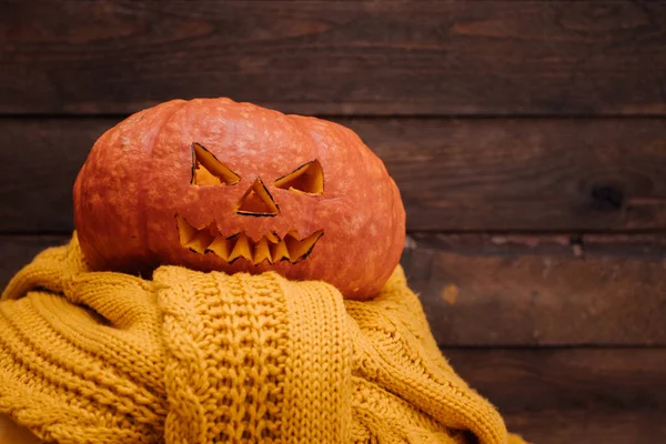 Dynia Halloween na żółtym swetrze i drewnianym tle — Zdjęcie stockowe