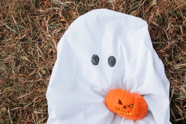 Duch kostium z halloween gospodarstwa rzeźbione dyni na jesiennym polu. — Zdjęcie stockowe