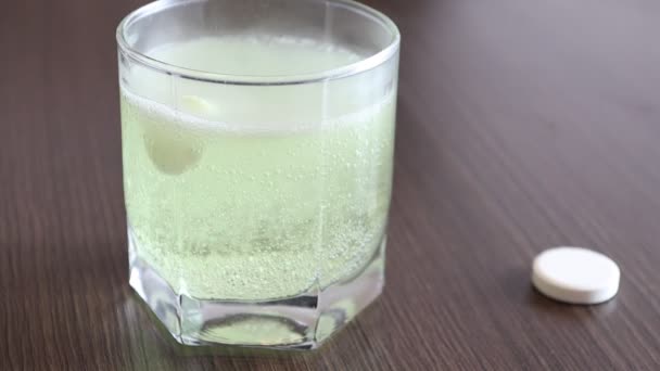 Comprimé jaune effervescent se dissout dans un verre transparent avec de l'eau — Video