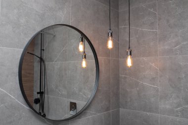 Modern karanlık banyoda asılı lambaları olan siyah yuvarlak ayna. Modern banyo iç mimarisi