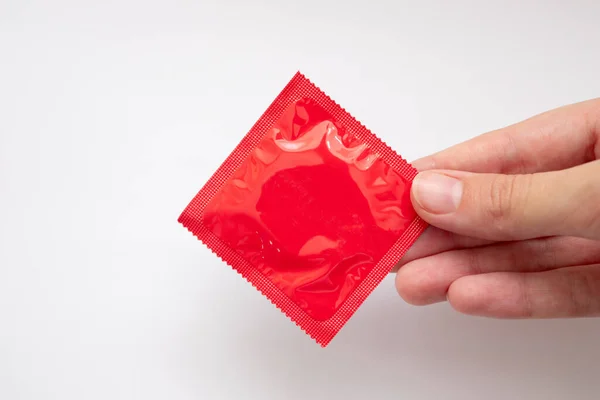 Hand Hält Rotes Kondom Auf Weißem Hintergrund — Stockfoto