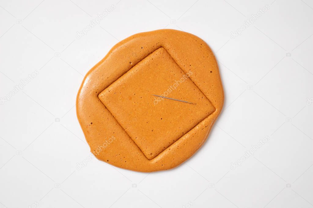 Korean Dalgona sugar candy cookie with a metal needle.