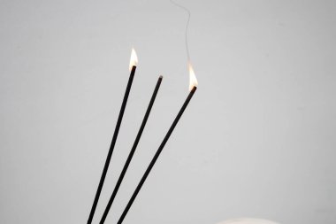 Beyaz arkaplanda yanan tütsü çubukları.