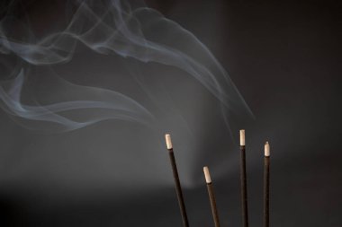 Yanan aromatik tütsü siyah arka planda duman bırakır..