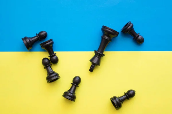 Bandeira ucraniana e peças de xadrez preto dispersas — Fotografia de Stock