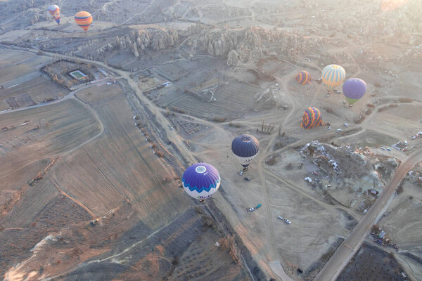 A lot of hot air balloons are flying over the mountainous terrain. Aerial photography