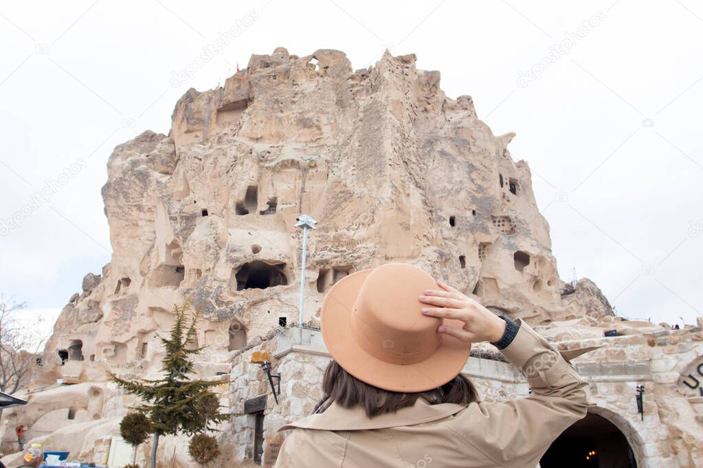 Travelling woman wearing brown hat looking at castle in Cappodocia