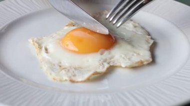 Bıçak ve çatal beyaz tabakta kızarmış yumurta..