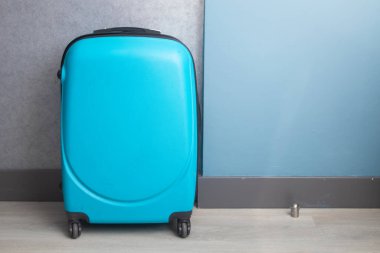 The blue suitcase is in the hotel room.