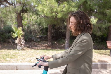 Elektrikli scooter kullanan ceketli genç bir kadın..