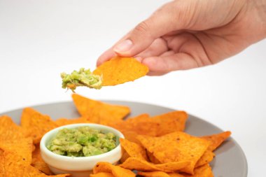 Guacamole soslu cips tutan bir kadın..
