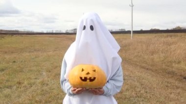 Sonbaharda oyulmuş balkabağıyla Cadılar Bayramı kostümlü çocuk.