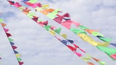 Güneşli bir günde gökyüzünde renkli bayraklar dalgalanıyor.