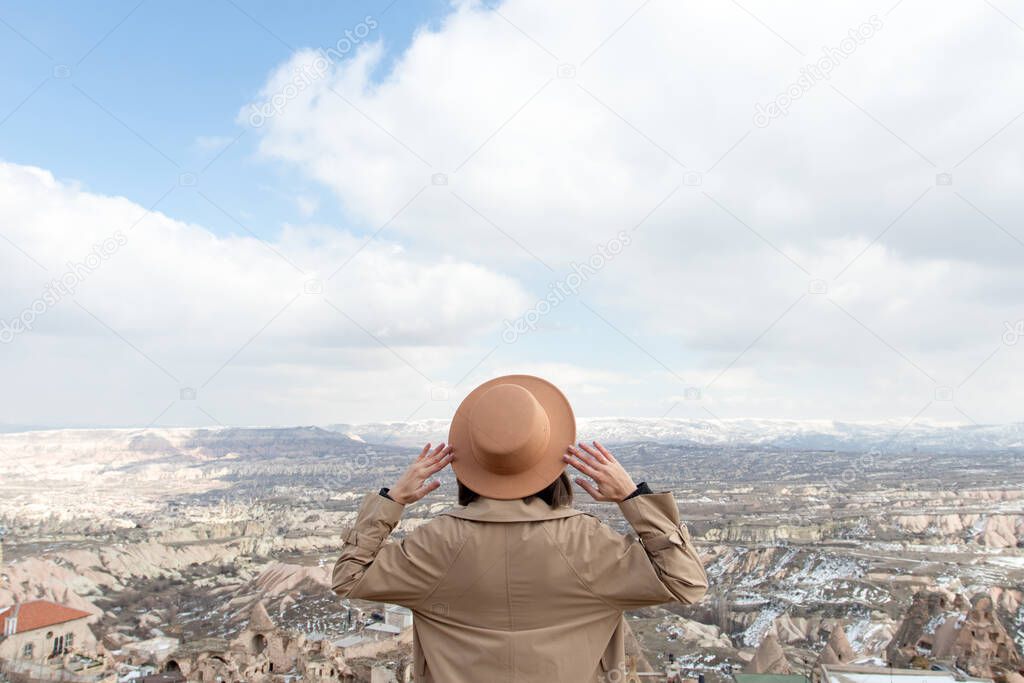 Woman in hat travelling at Cappadocia and looking valley.