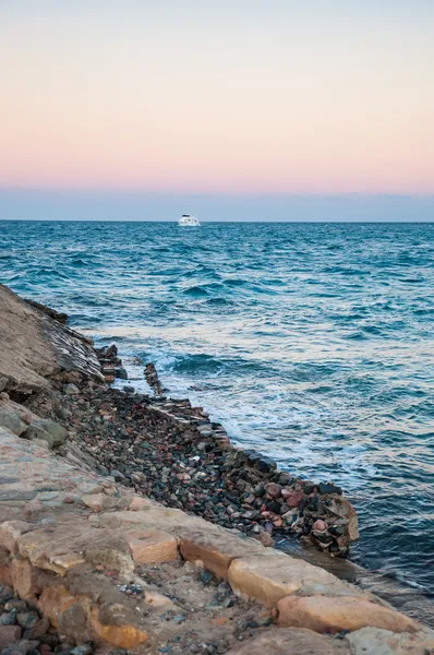 Sea coast and the yacht in the distance — Stock Photo, Image