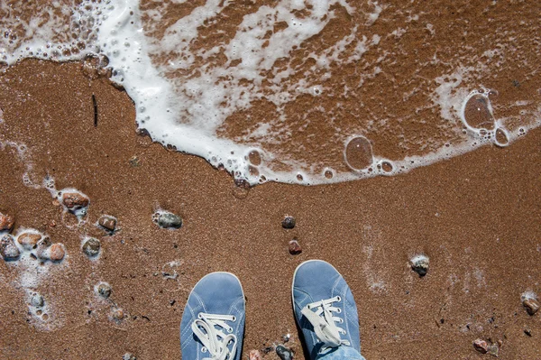 Foots of a woman standing on the sand by the sea — Stock Photo, Image