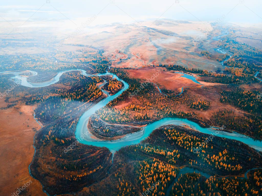 Chuya river in Kurai steppe, Altai mountains, Siberia, Russia. Aerial drone view. Blue river with yellow autumn trees with morning fog. Beautiful autumn landscape.