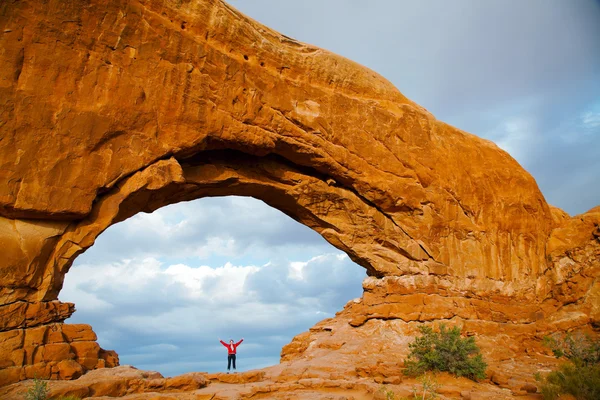 Mujer que se queda con las manos levantadas dentro de un arco — Foto de Stock