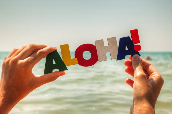 Main de femme tenant le mot coloré 'Aloha' Image En Vente