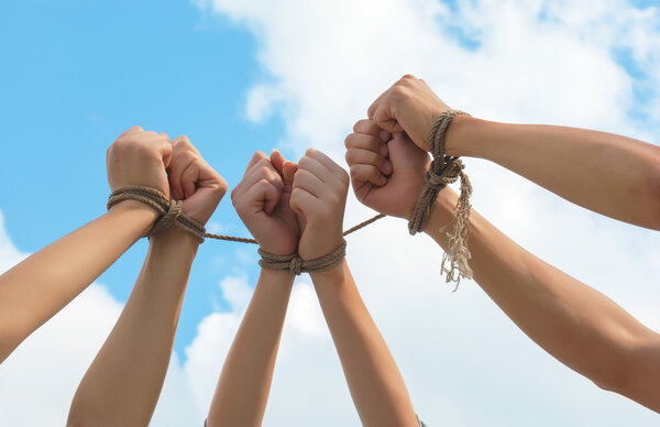 Three pairs of human hands tied up together