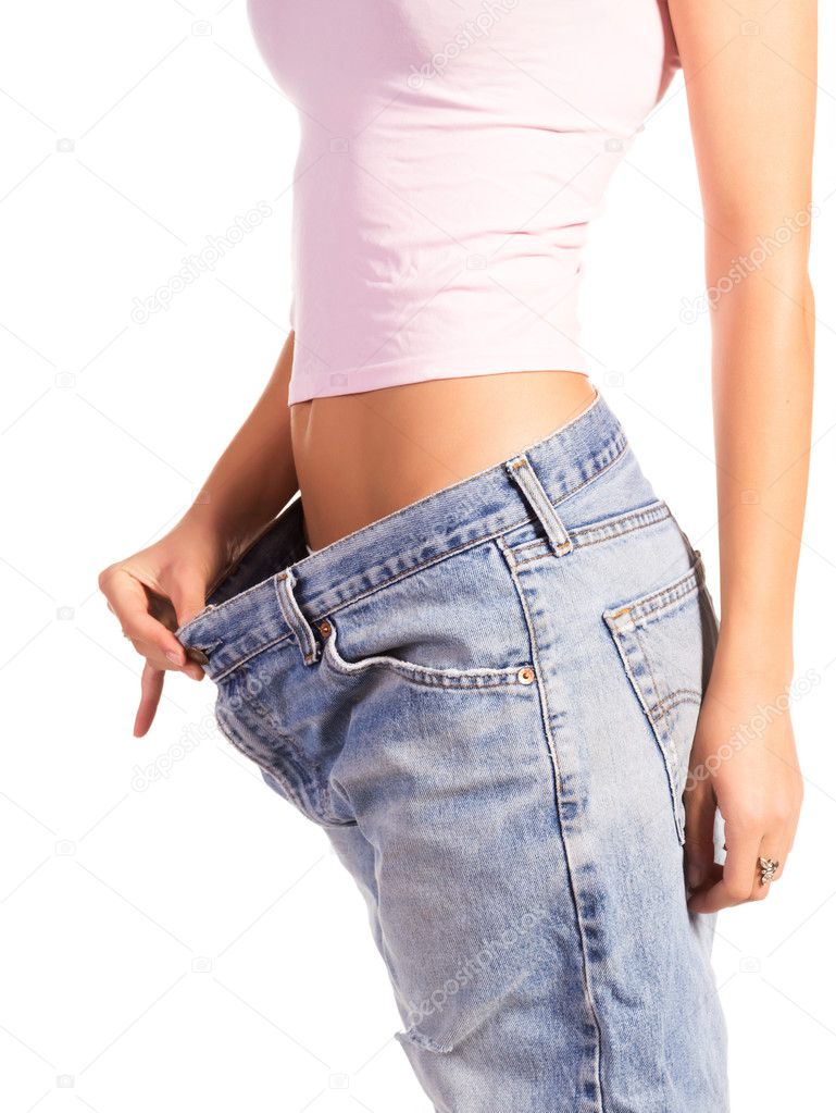 Woman shows her weight loss by wearing an old jeans, isolated on white background