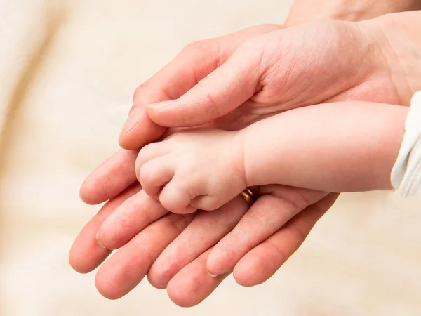 Closeup of baby hand into parents hands — Stock Photo, Image