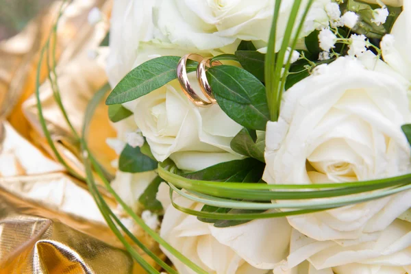 Bouquet of white roses with closeup of golden wedding rings on white rose — Stock Photo, Image