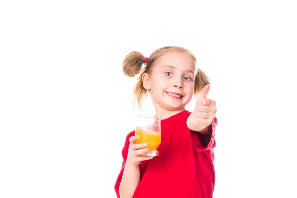 Ragazzina carina che tiene il bicchiere con il succo con il pollice in su — Foto Stock
