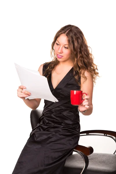 Привлекательная деловая женщина, читающая бумажки, наслаждаясь чашкой кофе — стоковое фото
