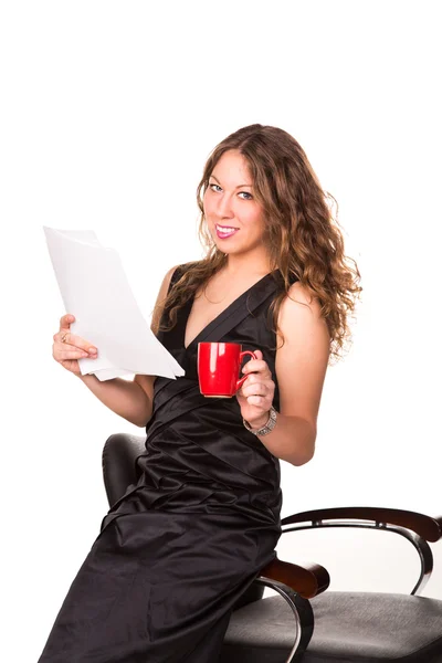 Attractive businesswoman reading paperwork while enjoying a cup of coffee — Stock Photo, Image