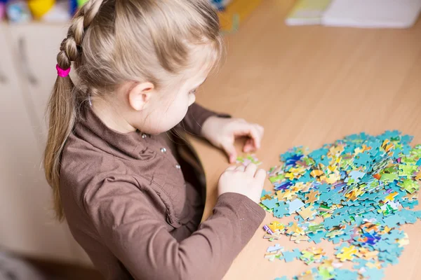 Cute little girl solving puzzles — Stok fotoğraf