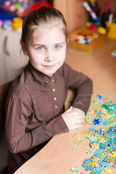 Cute little girl solving puzzles — Stok fotoğraf