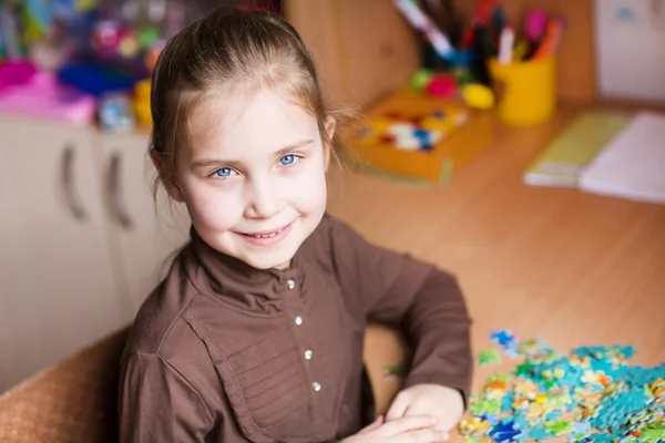 Cute little girl solving puzzles — Stock Photo, Image