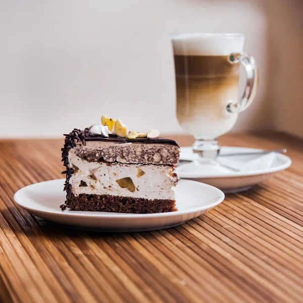 Un trozo de pastel de chocolate, café en el fondo — Foto de Stock