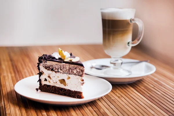 Un trozo de pastel de chocolate, café en el fondo — Foto de Stock