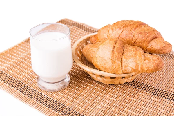 Croissants franceses frescos e saborosos em uma cesta com copo de leite — Fotografia de Stock