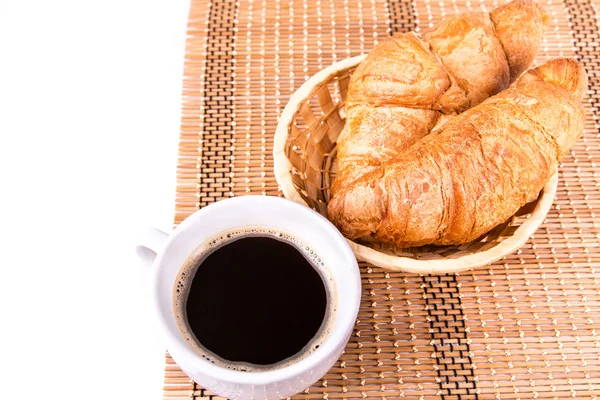 Croissants français frais et savoureux dans un panier et une tasse de café servis — Photo