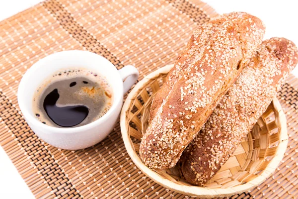 Rolos de pão recém-assados com gergelim com xícara de café — Fotografia de Stock