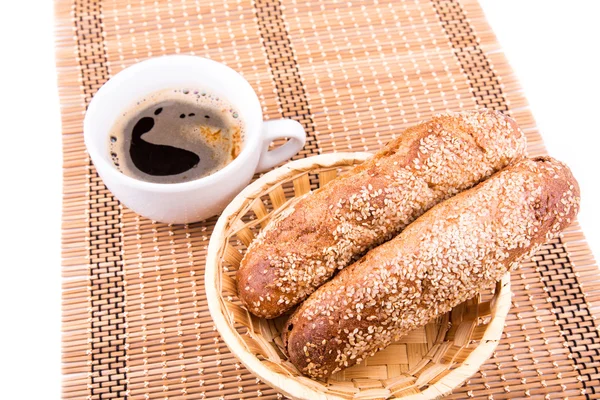 Rolos de pão recém-assados com gergelim com xícara de café — Fotografia de Stock