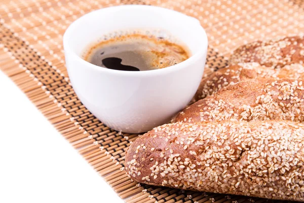 Rolos de pão recém-assados com gergelim com xícara de café — Fotografia de Stock