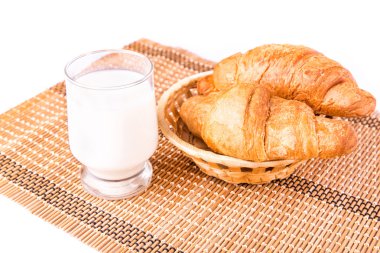 lezzetli ve taze kruvasanlar bir sepette bardak süt ile Fransız